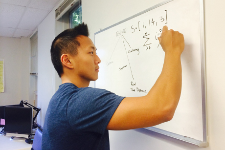  team member outlines an algorithm on white board