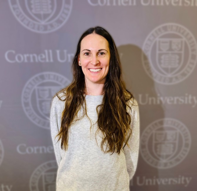 Lauren Frederick posing in front of Cornell logo backdrop