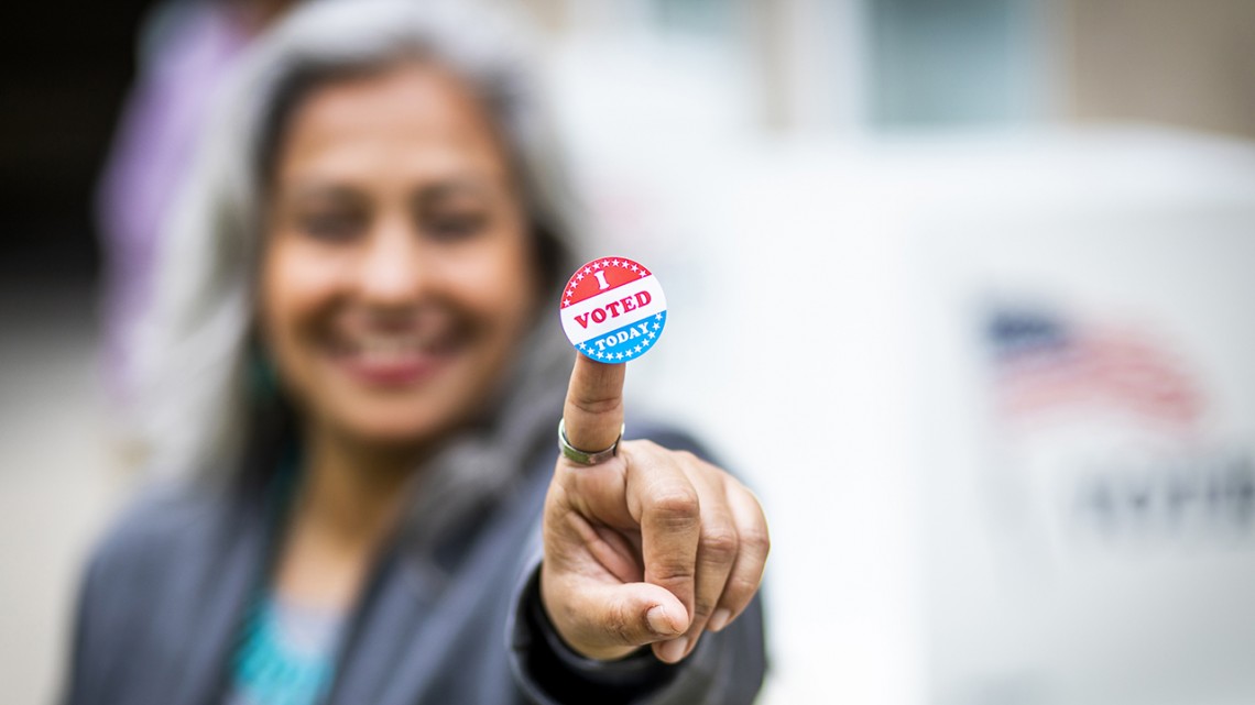 Woman holding voting sticker toward camera