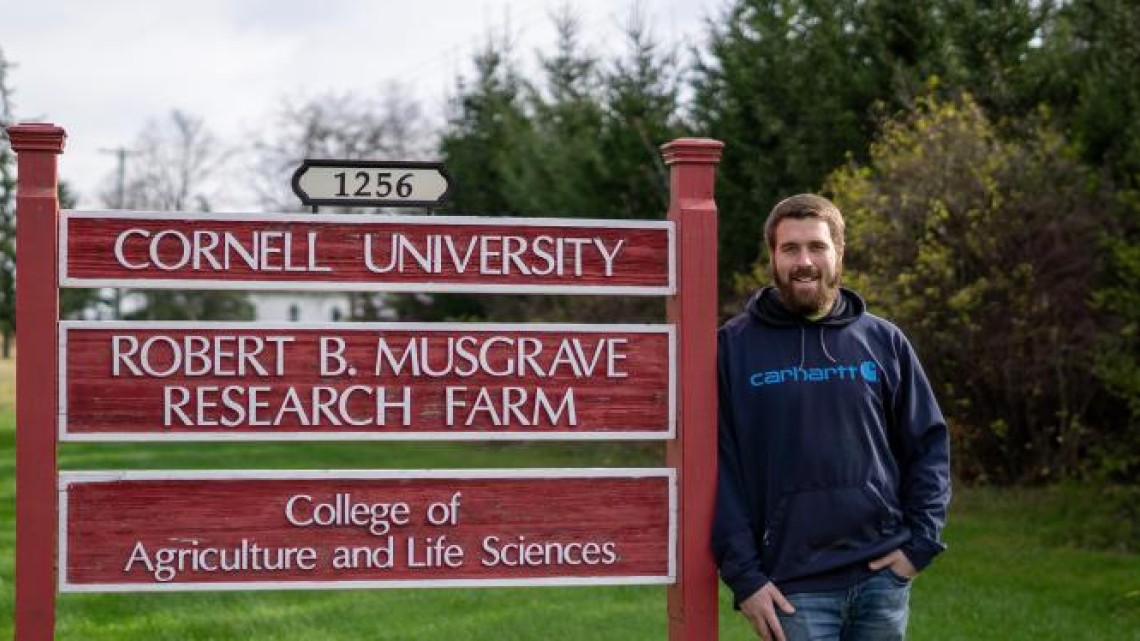 man standing by the musgrave research farm sign