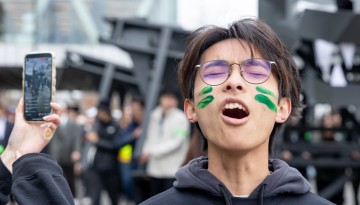 A young man with face paint yelling. 