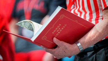 A man holds the hardcover 'Songs of Cornell' book. 