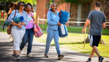 A family carrying possessions to a residence hall. 