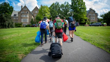 Students pulling their luggage across North Campus. 