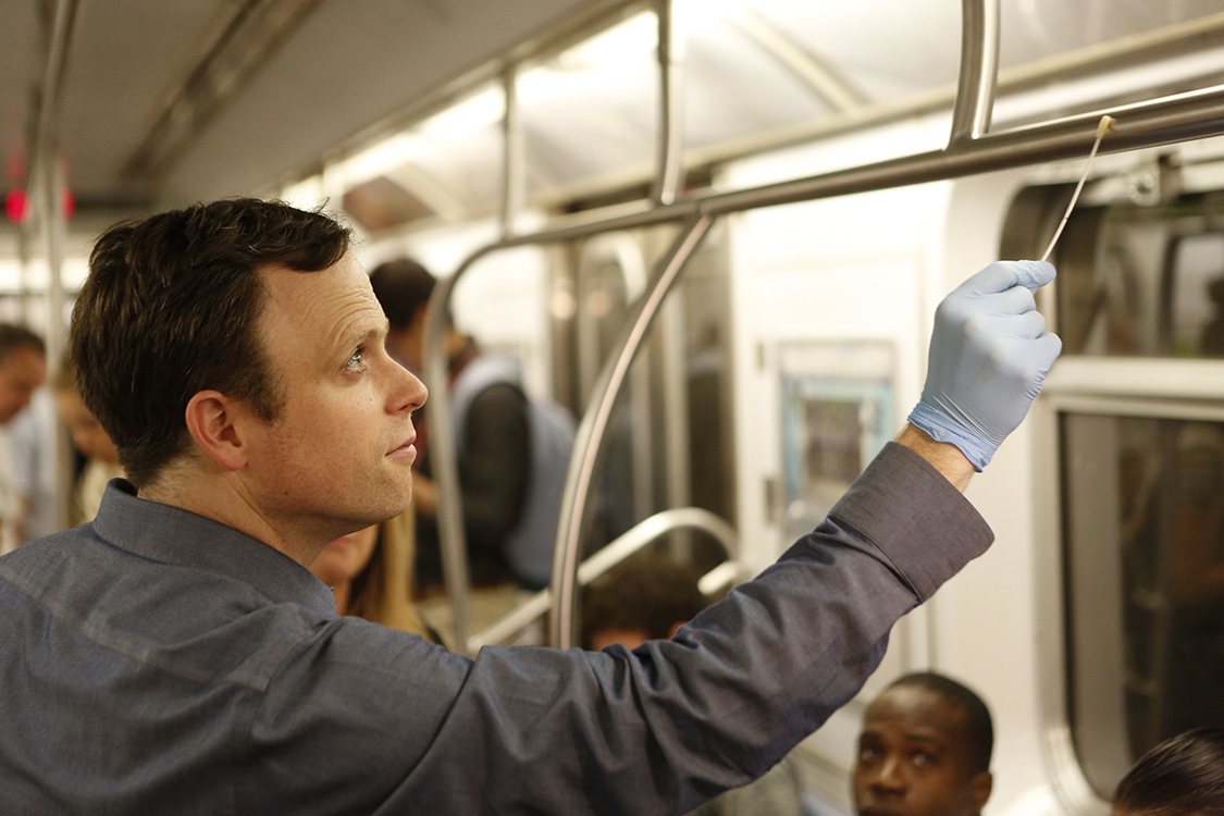 Dr. Christopher Mason swabs a subway car handrail
