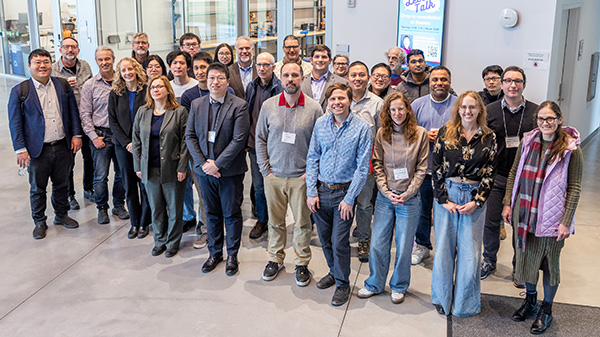 About 40 people stand outside of a classroom in an academic building
