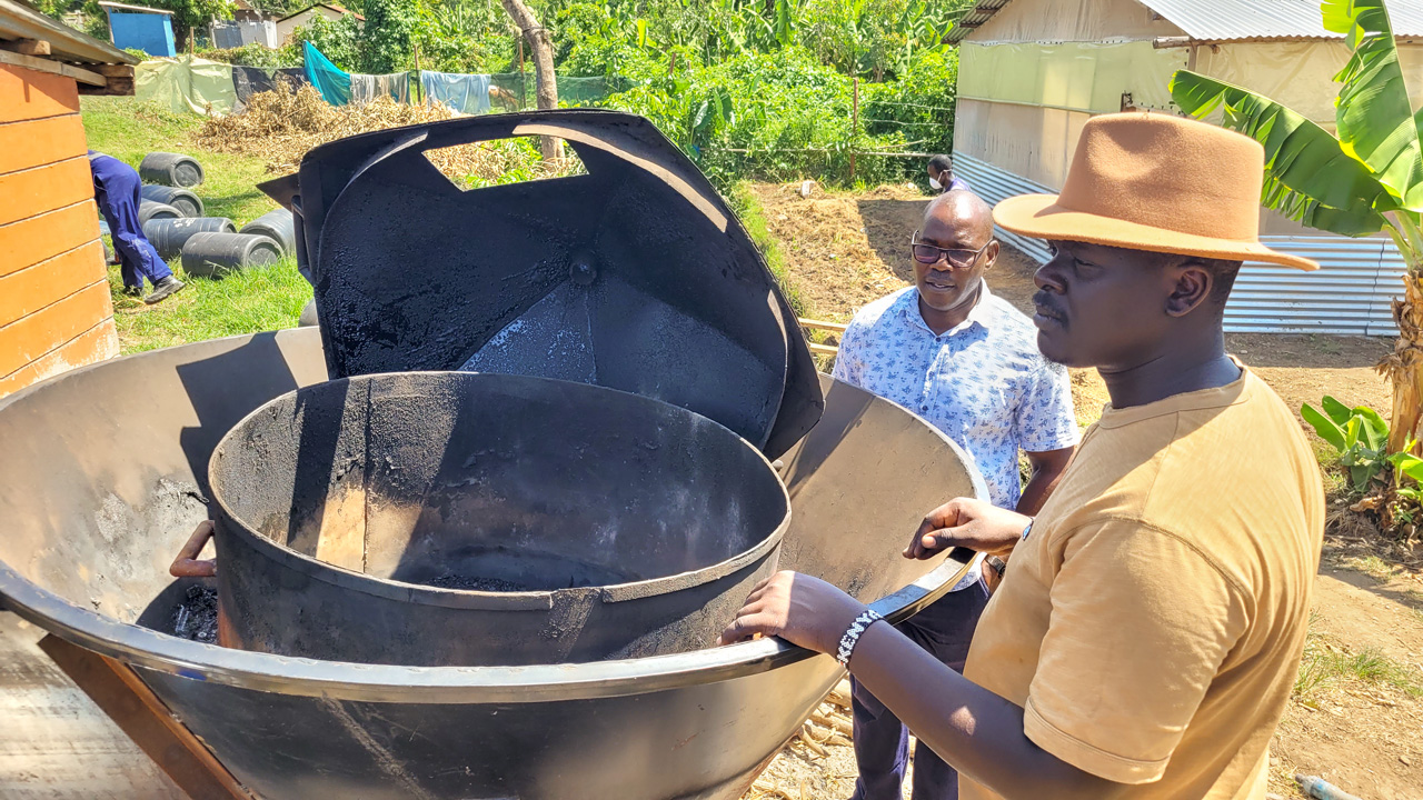 Charles Midega (left) and Roy Odawa display the Kontiki kiln they modified to make biochar from human feces.