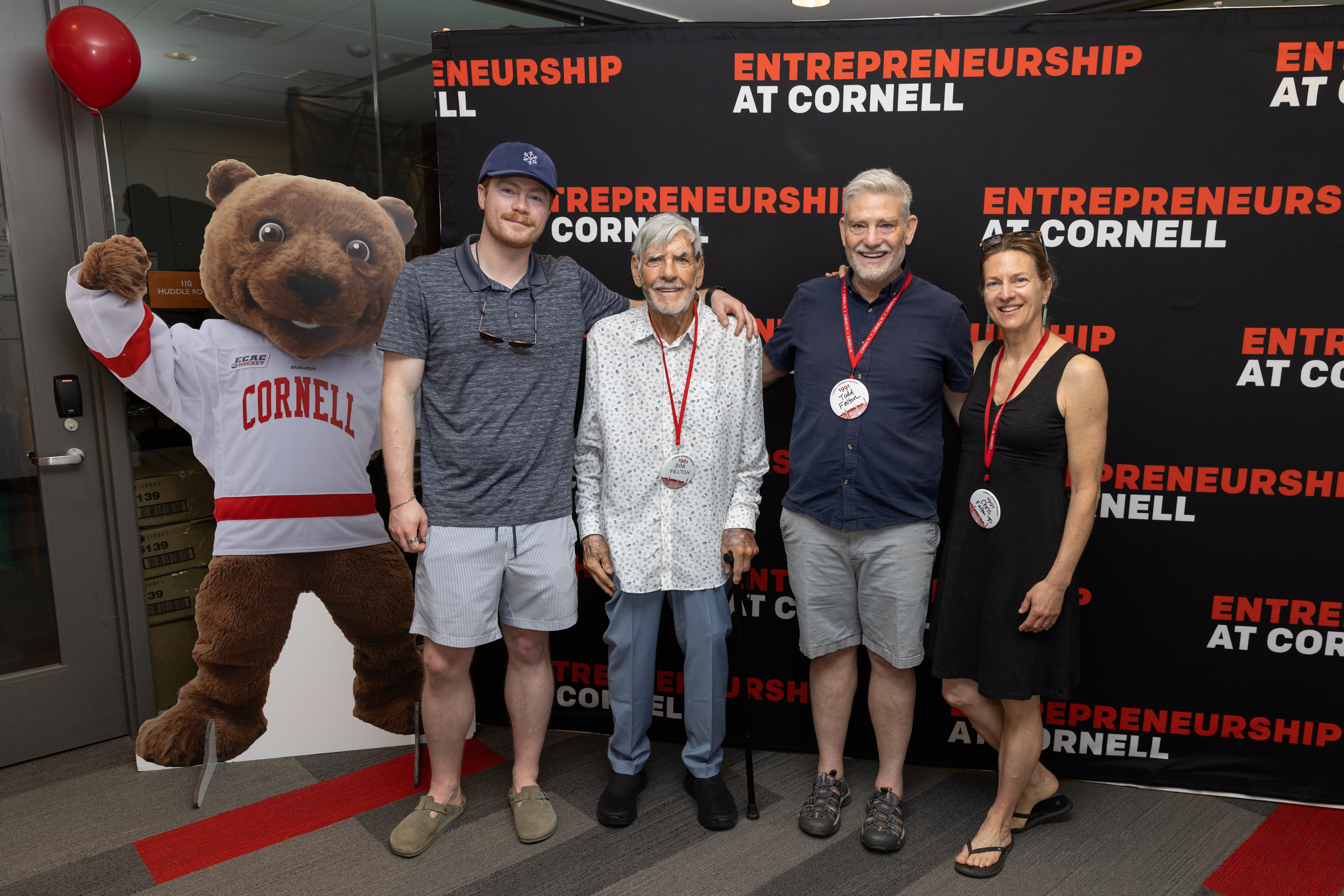 Four people standing next to a cutout of Touchdown the Bear 