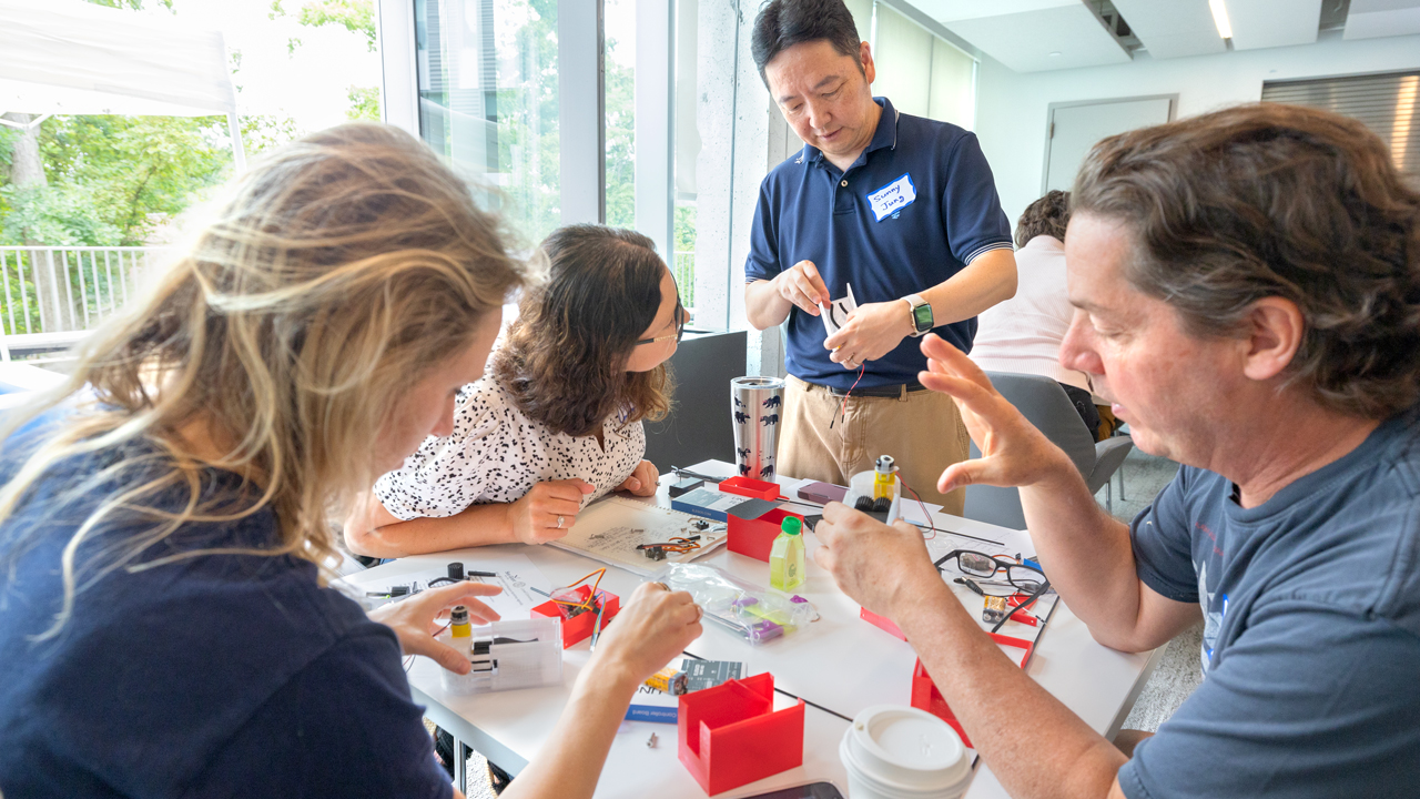 Professor Sunny Jung (standing) helps teachers assemble a robot