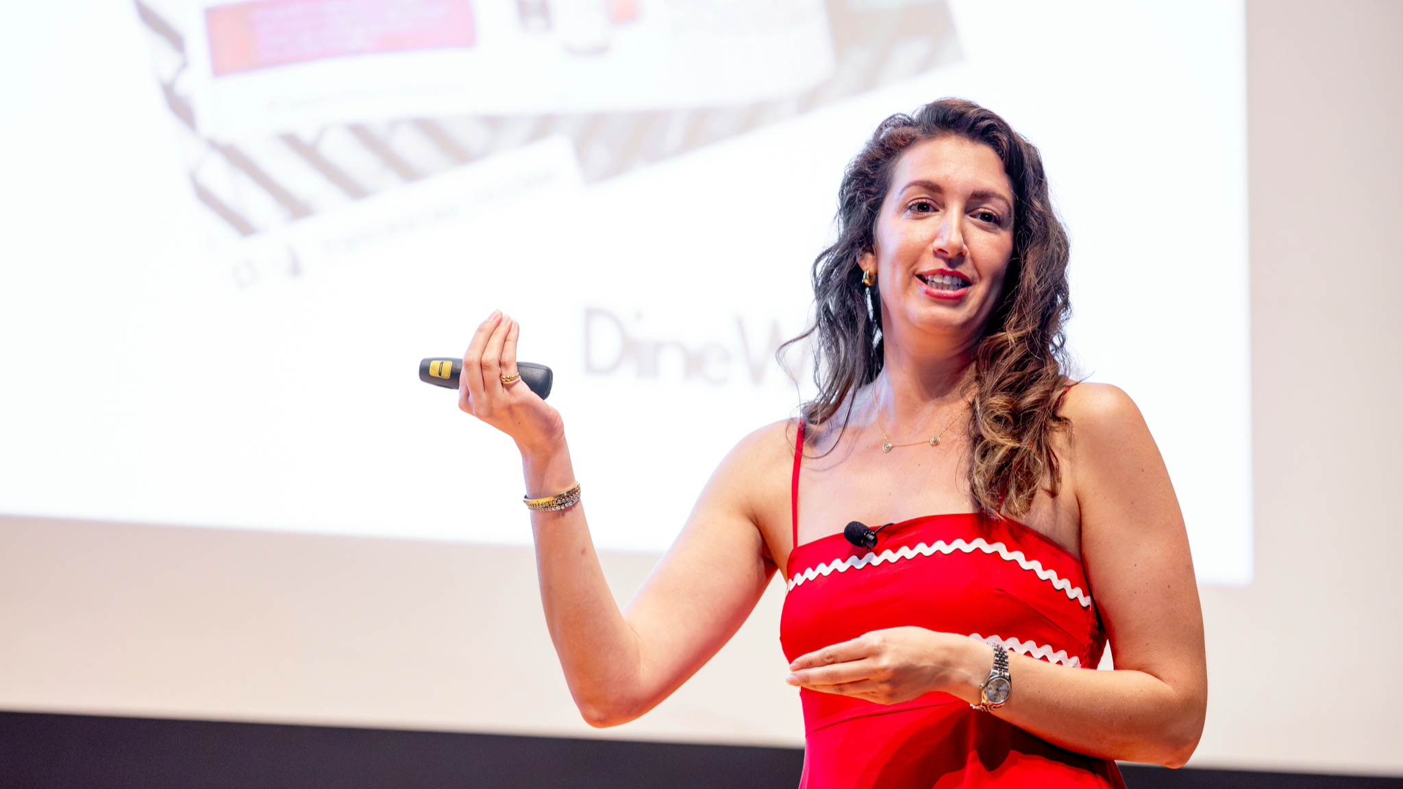 Dana Beninati '15 in a red dress in front of a large screen during a presentation.
