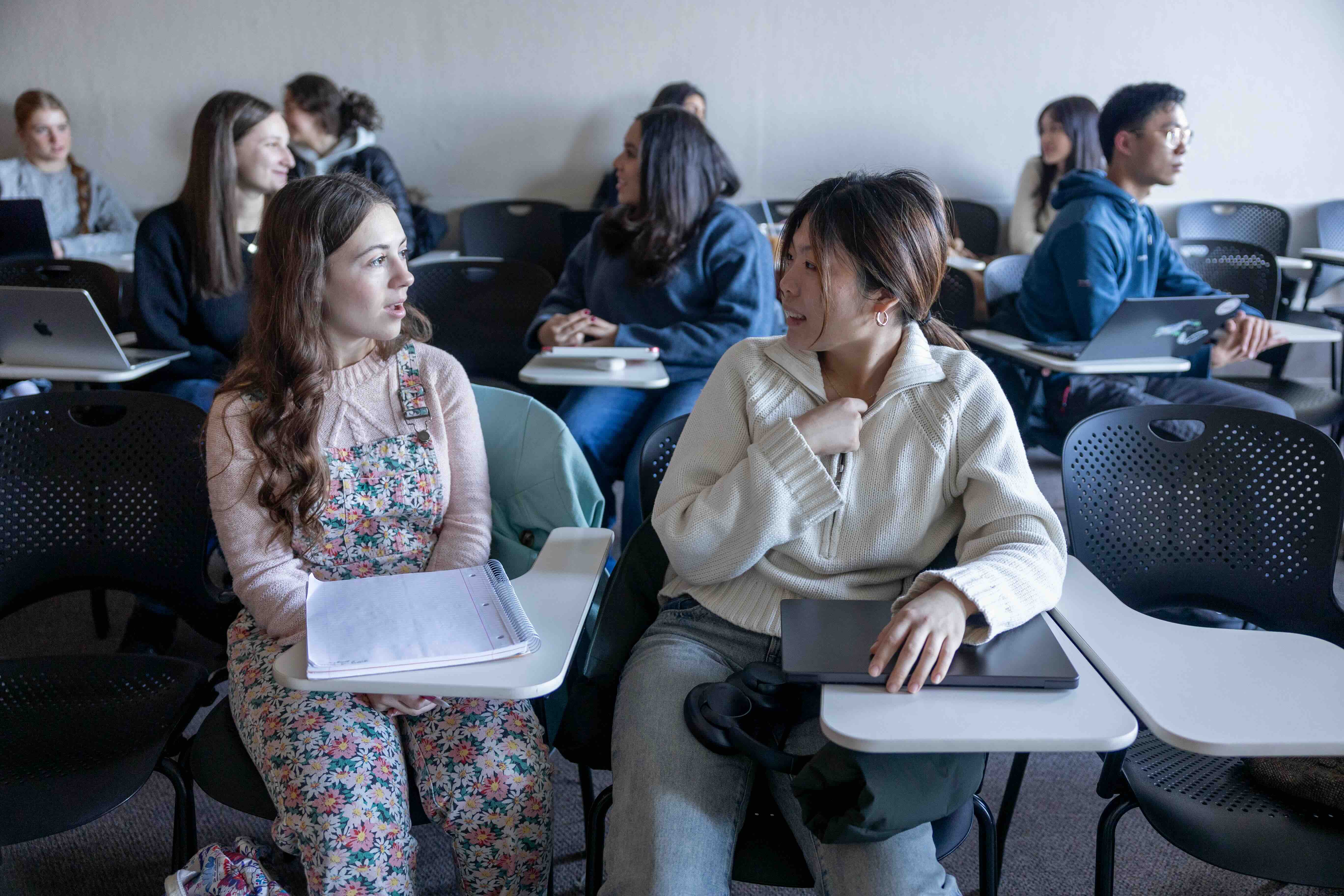 two students talking in a classroom