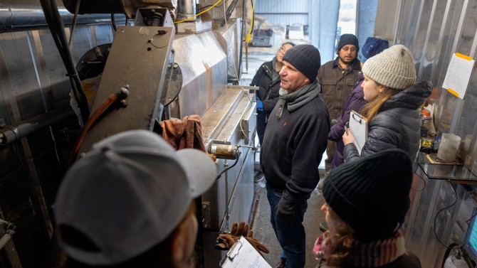 Cornell professor Johannes Lehmann, center, examines the biochar kiln at Spruce Haven Farm with officials from NYSERDA and Arcadis in November.