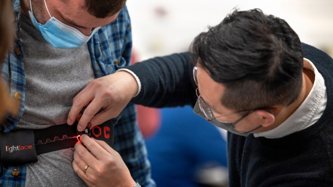 Jeyeon Jo, doctoral student in apparel design, straps a fiber-optic sensor on ORC mechanical engineer Tommy Sipple.