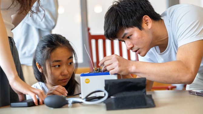Sophia Lin ’25, left, and Steven Sun ’25, right, set up their all-in-one device that transmits blood pressure data via low-frequency radio waves. 