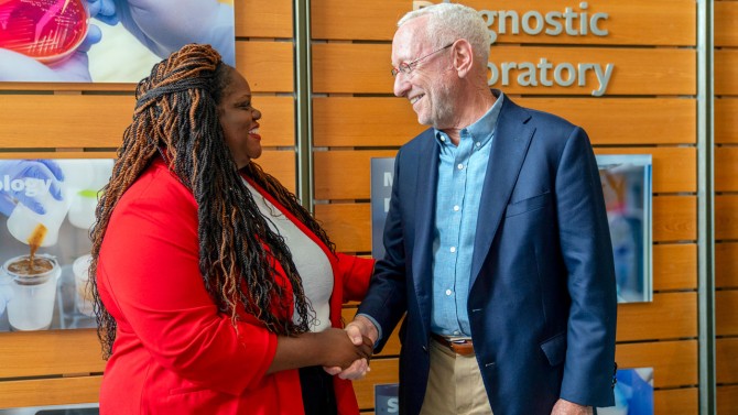 State Sen. Lea Webb and Interim President Michael Kotlikoff shake hands after the announcement.