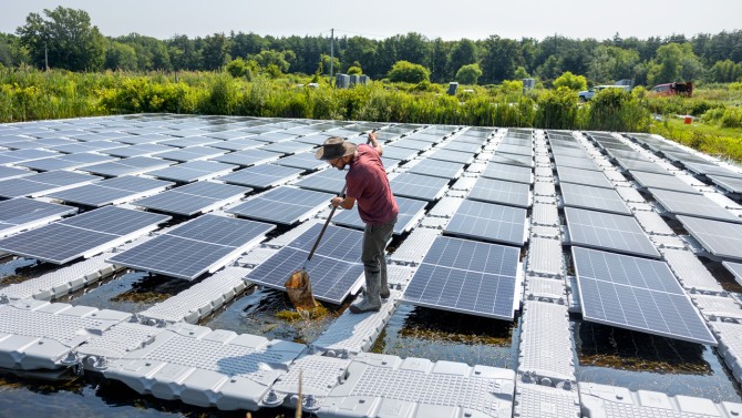 Steve Grodsky, assistant professor, samples arthropods on a solar panel-covered pond at the Cornell Experimental Pond Facility.