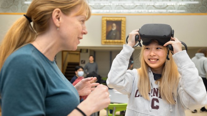 Kim Benowski, left, a staff member from Cornell’s Center for Teaching Innovation, helps a student use a VR headset as she learns a complicated microscope technique in a molecular biology and genetics class.