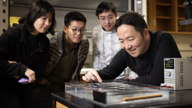 Sunny Jung, professor of biological and environmental engineering (far right) and study coauthors (from left), Jisoo Yuk, Chris Roh and Yicong Fu, watch a demonstration of their snail-inspired robot.