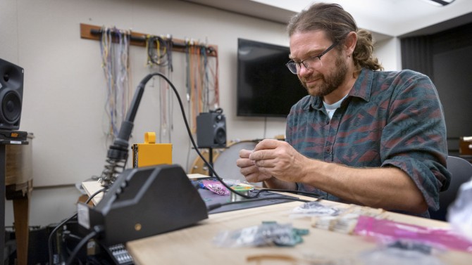 Travis Johns works on soldering microchips for the reimagined Moog keyboard in Lincoln Hall.