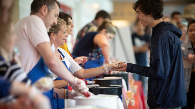 A student receives a sampling of ice cream at the 2018 Summer Scoop.
