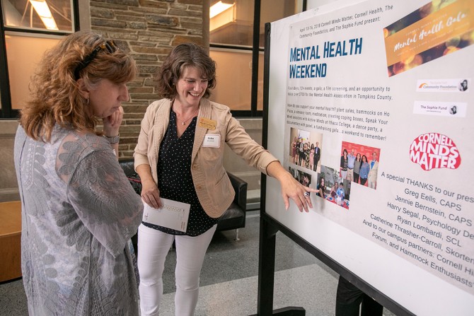 Reba McCutcheon, associate dean of students, explains a photograph to Kristine DeLuca, director of the Cornell Commitment Office.