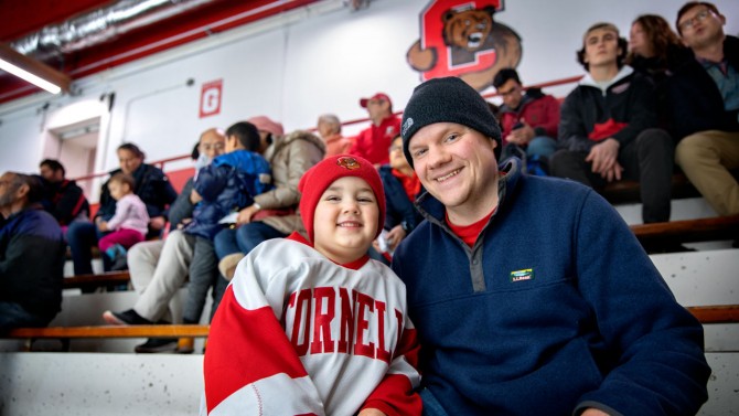 David Winisrski enjoys the hockey game with James during the 2019 Winter Employee Celebration in Lynah Rink.