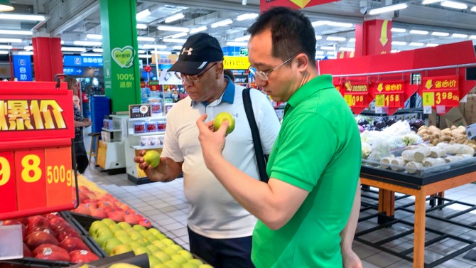 two men inspecing apples at a Chinese grocery store