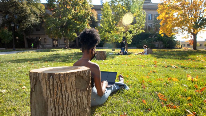 A student uses a recycled log as a backrest on the Ag Quad