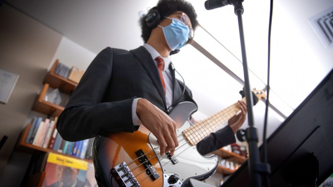Student in suite with mask playing the bass