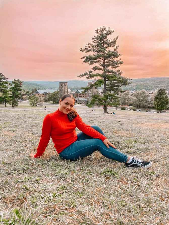 Person wearing red sweater poses on a hillside