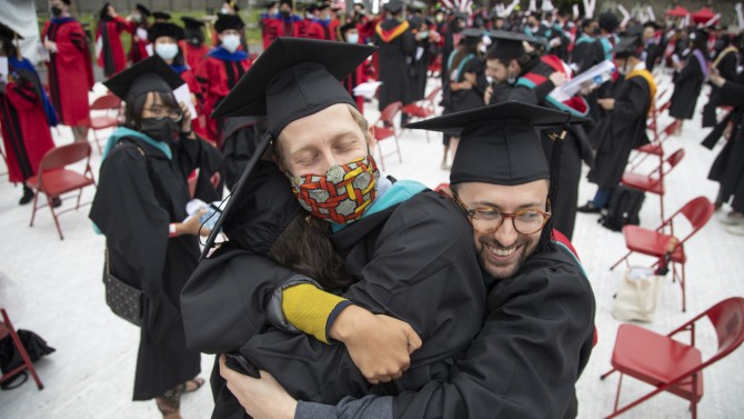 New graduates embrace on Schoellkopf Field. This was the first in person graduation since December 2019.