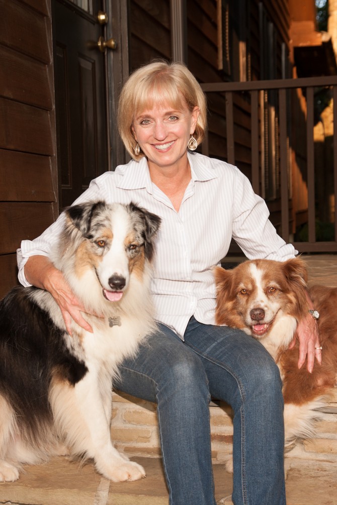 Sheila Allen seated, holding close to her two Australian shepherds