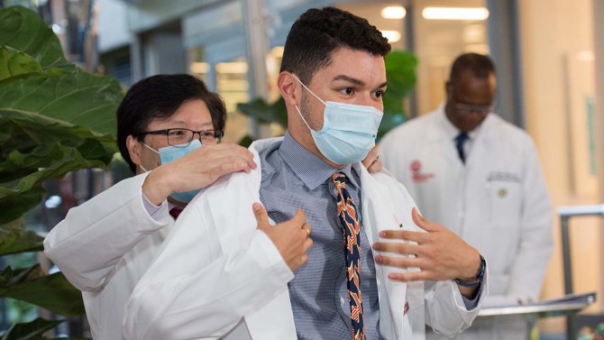 Second-year medical student Rafael Almanza receives his short white coat from Dean Choi.