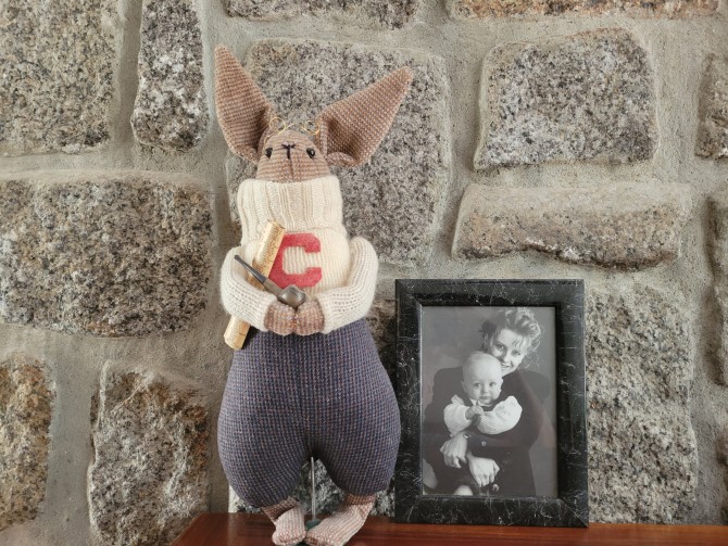 Stuffed animal rabbit sits next to a framed photo on a mantle