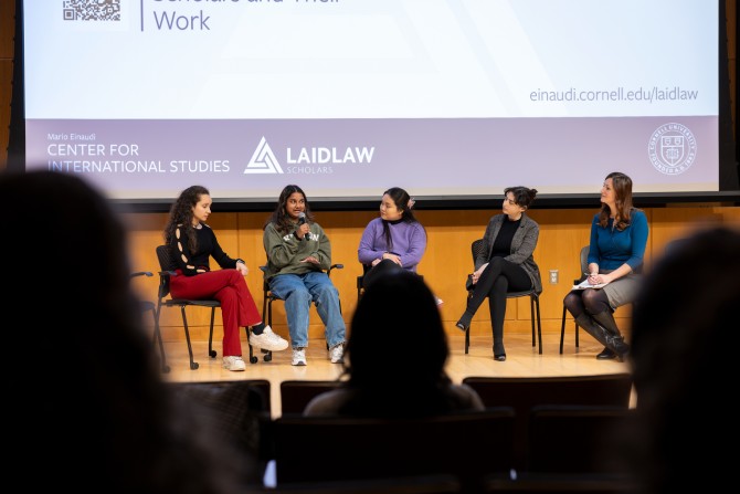A panel of Laidlaw scholars sit on a stage and hold microphones. 