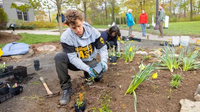 Allen Gelfond '25, and Kaitlin Fisher '24, team co-leader in the Cornell Botanic Gardens' Learning by Leading Program, plant along the outer edge of the circular garden plot at Akwe:kon.