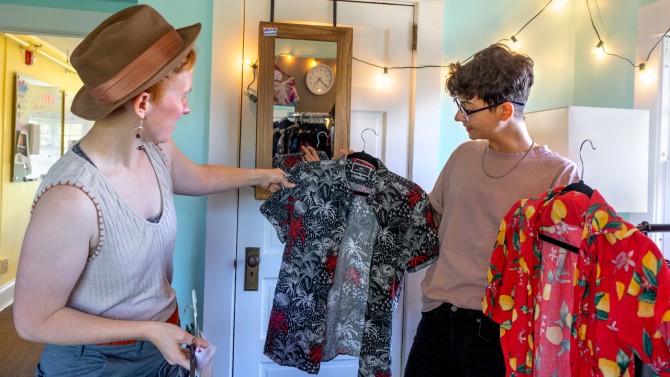 Students look at shirts on hangers