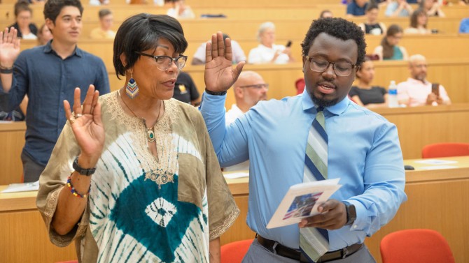 Michael Adelien, right, takes his oath during a naturalization ceremony. Originally from Haiti and an undergraduate at Cornell studying information science, his ambition is to help modern technologies to be more inclusive of marginalized people.