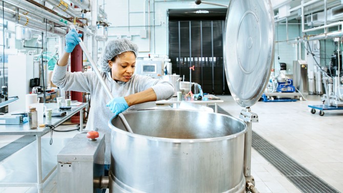 Woman stirring item in vat