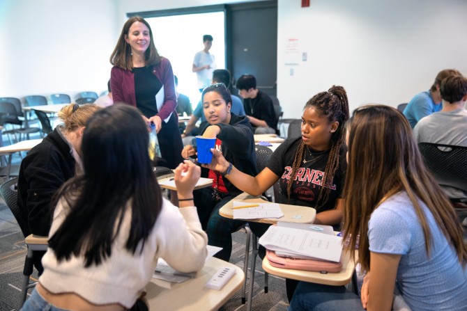 About six students interact while an instructor stands by