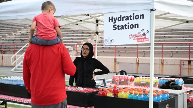 A father and son view their options of Gatorade, chocolate milk and water at the hydration station at Schoellkopf Field during the first Cornell Community Field Day.