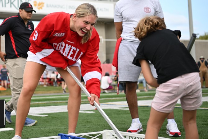 Cornell women’s hockey player Lindzi Avar plays box hockey with a young girl.