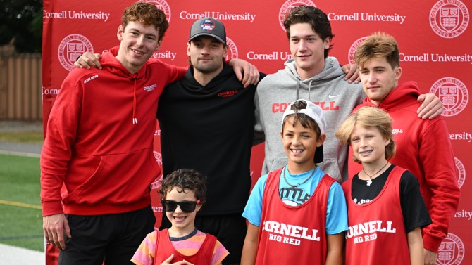 Families take photos with Cornell Men’s Hockey players (left to right) Hank Kempf, Tim Rego, Kyle Penney and Jack O’Leary, at the hockey photo booth.