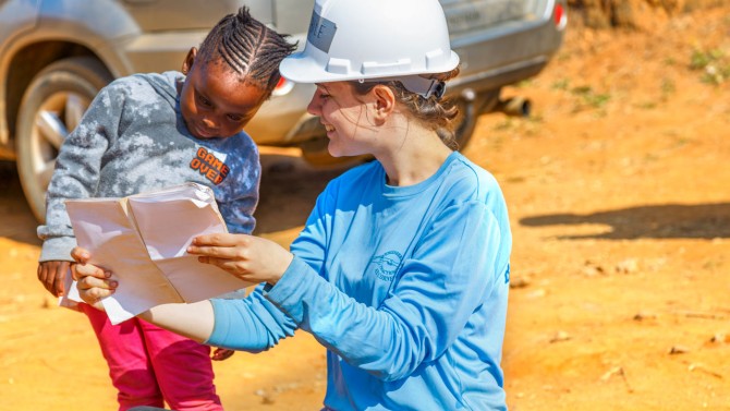 Sara Buchta ’25, an environmental engineering major and the project manager for Cornell Engineers in Action, shares plans for a groundwater system with a student at Matfuntini Primary School in rural Eswatini.