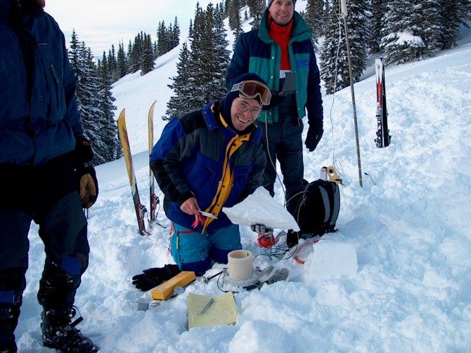 man kneels in snow with electronic devices near him