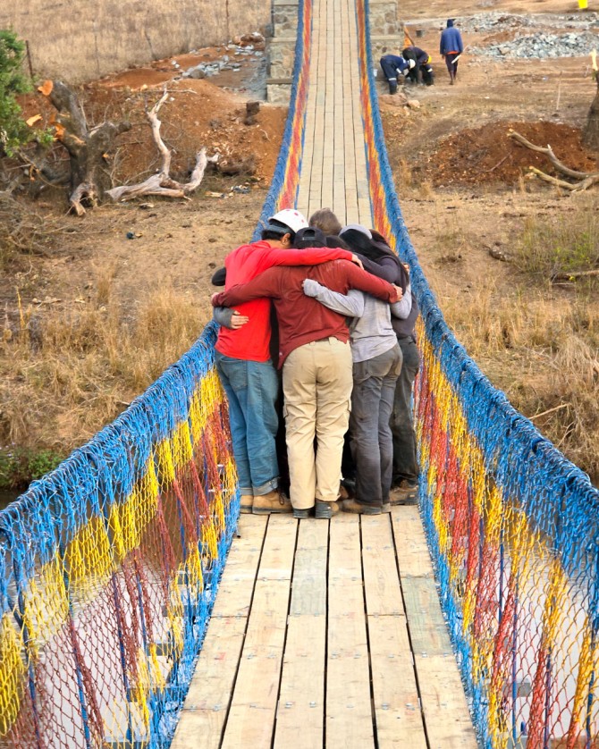 The Cornell Engineers in Action team huddles with their community partners on the completed Jolitane bridge in Eswatini.