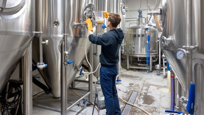 Alex Goerler, assistant brewer at Liquid State Brewing Company, monitors carbonization in a batch of beer.