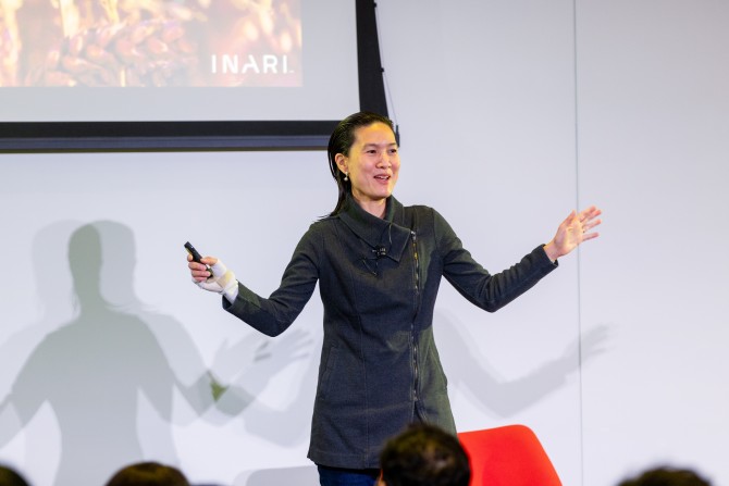 a woman speaking to a crowd in a conference room 