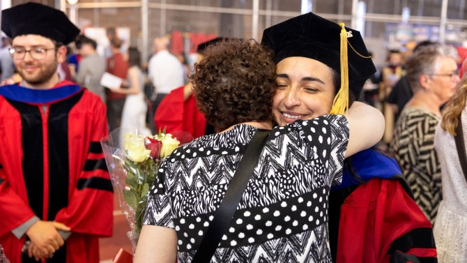A newly recognized Ph.D. recipient embraces family after the ceremony.
