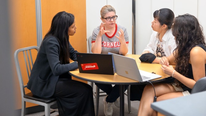 Fatma Baytar, Ph.D. ’11, (center left), assistant professor of human centered design in the College of Human Ecology, discusses swim cap design with entrepreneur Saira Patel (left) and graduate students Yoon Yang, M.A. ’22, (center right) and Ivania Rivera, M.S. ’24, (right).